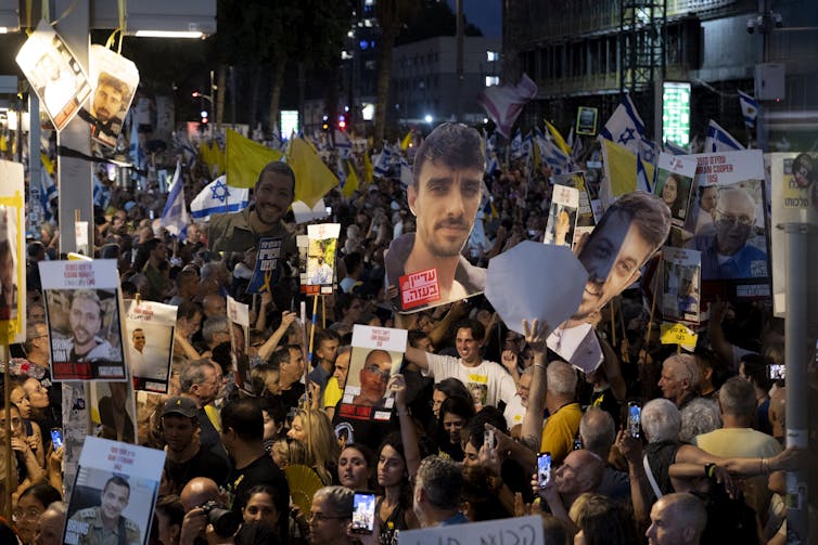 People hold aloft placards and imges of men's faces/